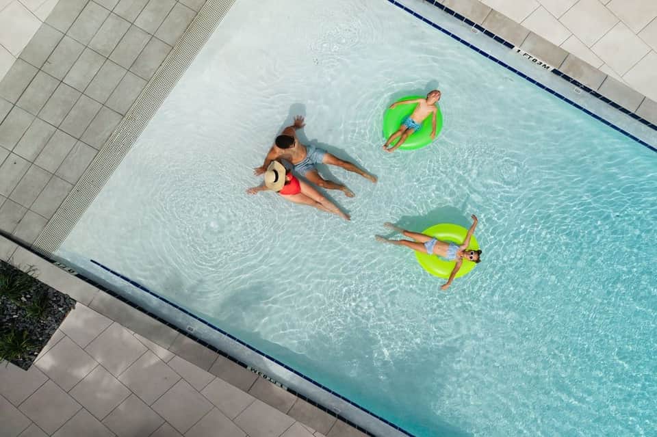 Overhead view of family enjoying indoor pool with colorful float rings in clear turquoise water