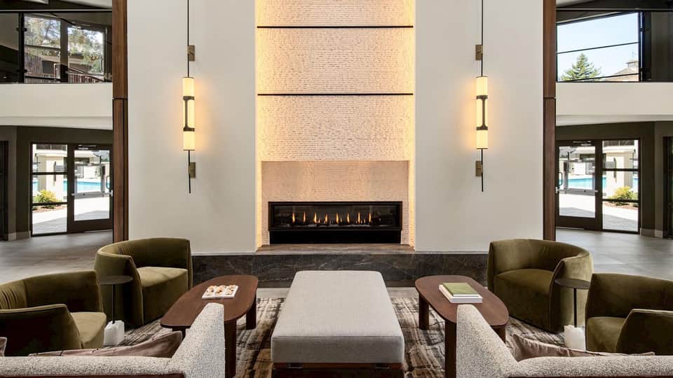 Modern hotel lobby with fireplace, contemporary lighting, and earth-tone seating