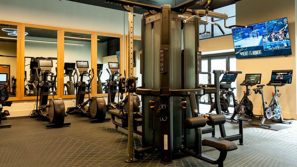State-of-the-art fitness center with cardio equipment, weight machines, mirrors, and TV screens