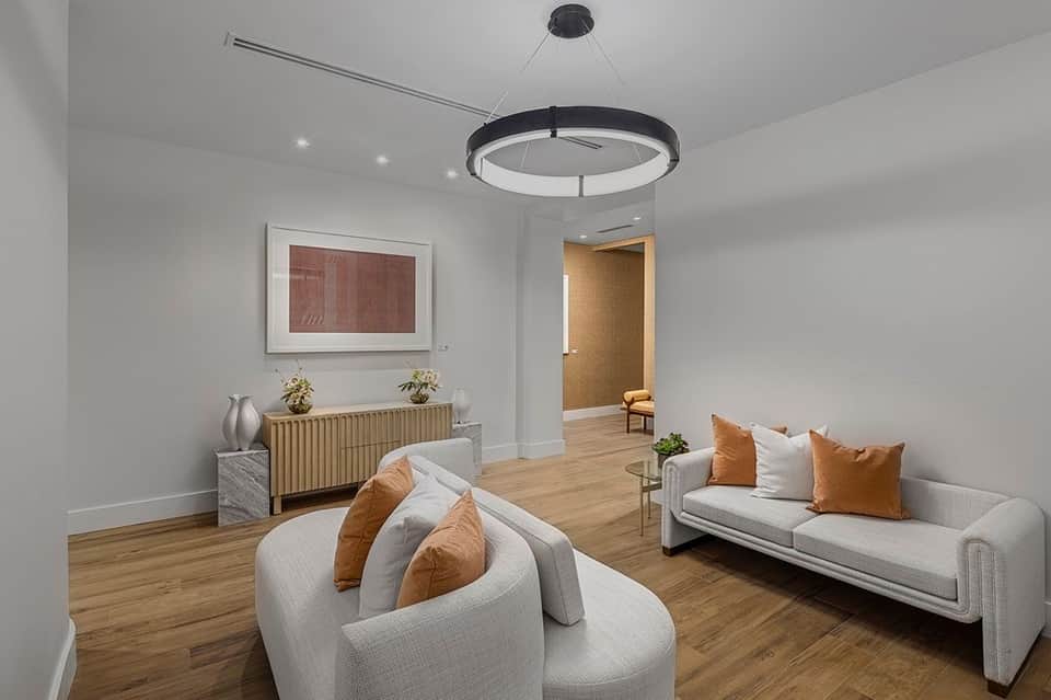 Modern spa lounge with white curved seating, wooden accents, and contemporary circular pendant lighting