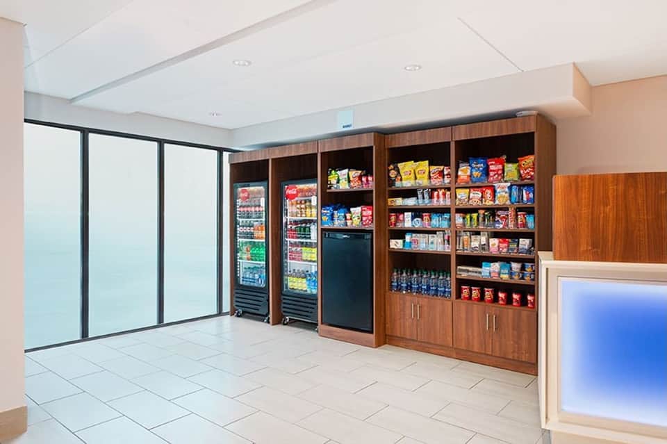 Hotel convenience store with refrigerated beverage cases, snack shelves, and vending machines