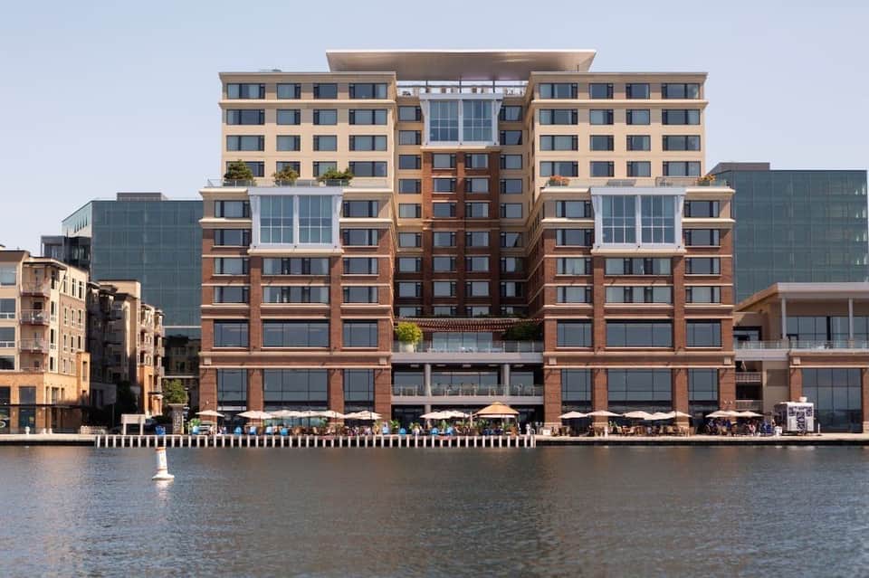 Modern brick waterfront building with multiple floors reflected in calm water