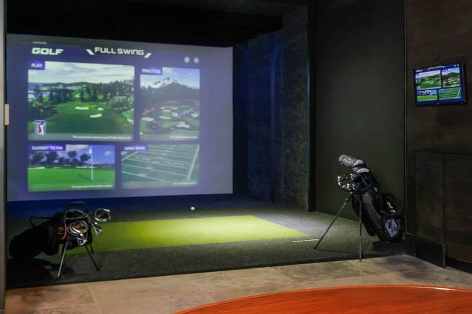 Indoor golf simulator room with Full Swing system, large display screen, and professional equipment