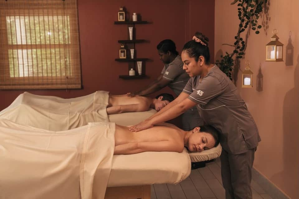 Spa massage room with therapists providing relaxation treatment to two clients on massage beds