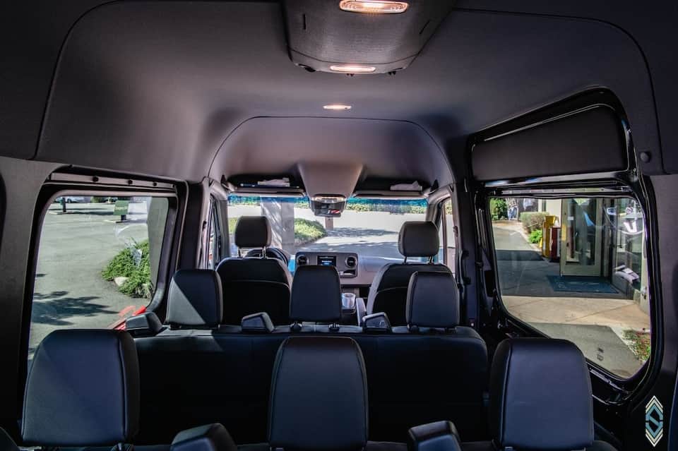 Van interior with black seating, windows, and front dashboard view