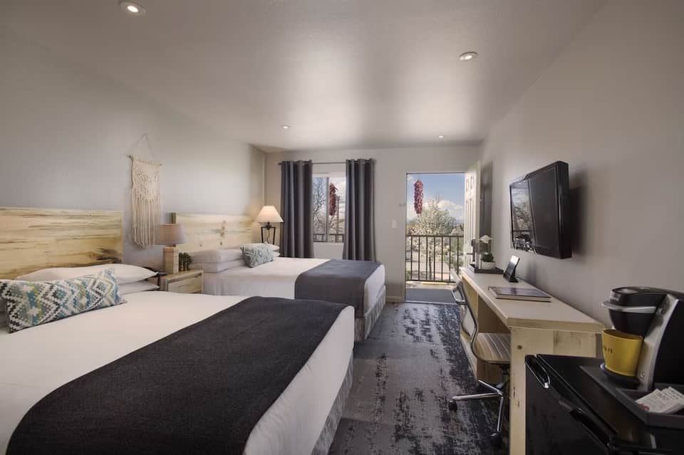 Hotel room with two queen beds, wooden furniture, TV, balcony access, and contemporary décor