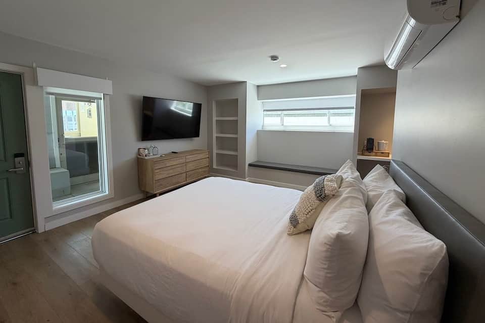 Master bedroom with king bed, TV, wooden dresser, ensuite bathroom, and sliding glass patio door