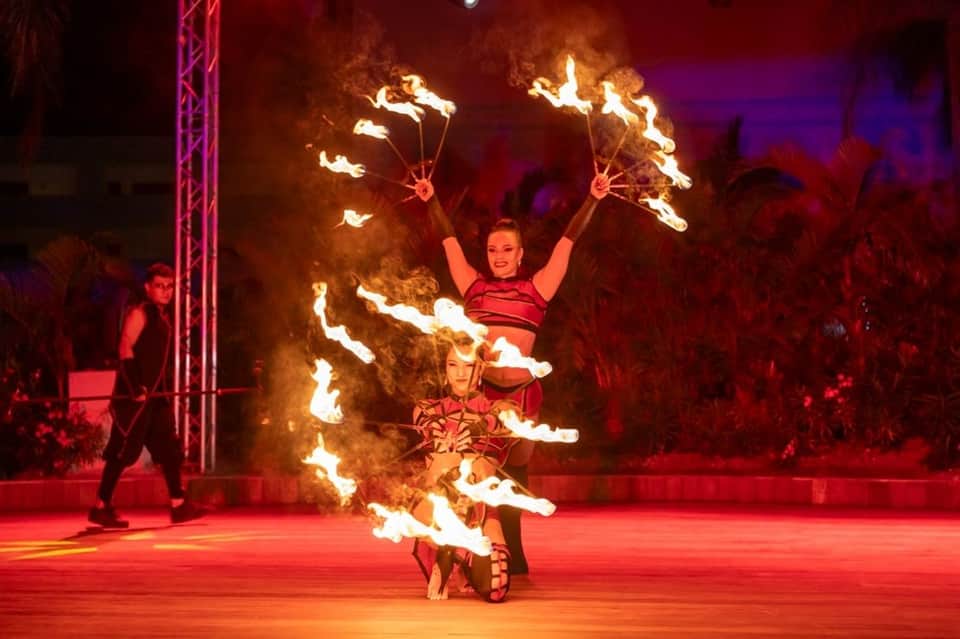 Fire performers in red costumes on stage during evening entertainment show