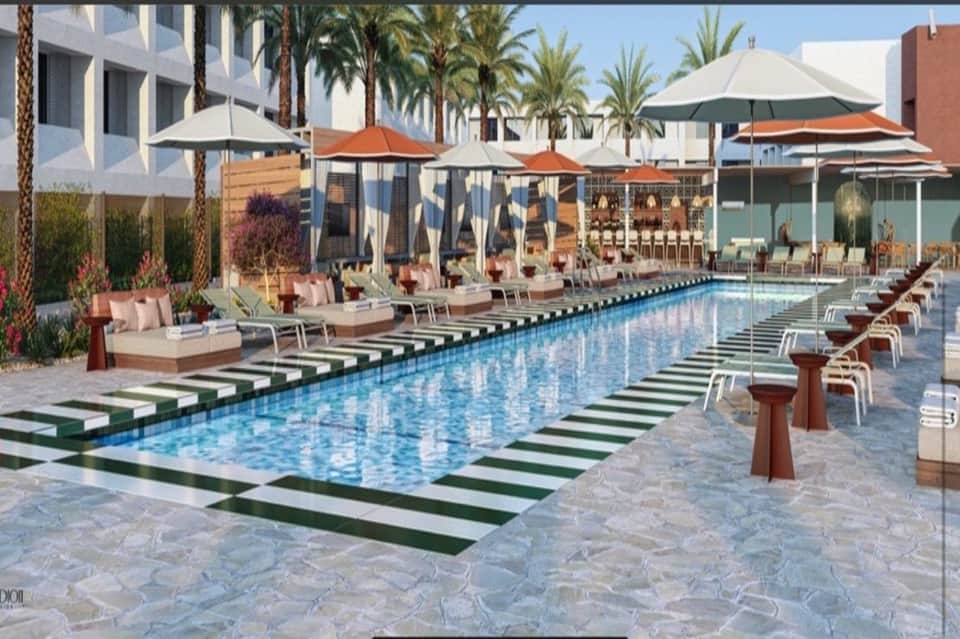Luxurious pool deck with striped lounge chairs, orange umbrellas, palm trees, and modern architecture