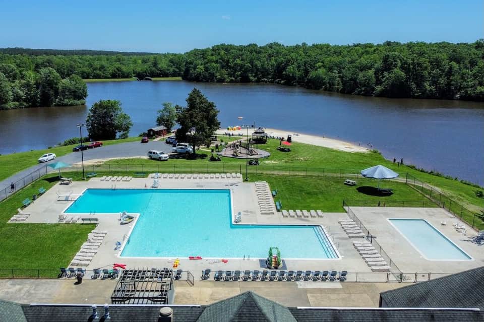Aerial view of resort with multiple pools, river beach, playgrounds, and expansive waterfront