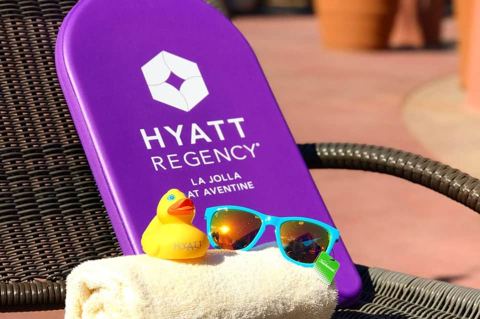 Hyatt Regency La Jolla poolside items: purple branded board, colorful sunglasses, beach towel