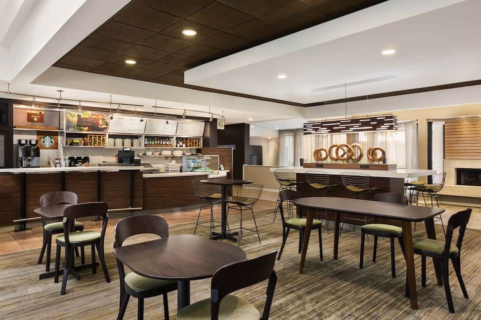 Upscale cafe lounge with coffee bar, Starbucks signage, dining tables, and decorative gold accents