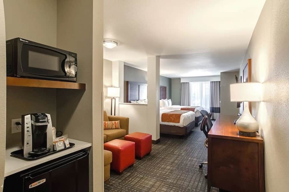 Hotel suite with bedroom, seating area, coffee maker, and warm wood furnishings