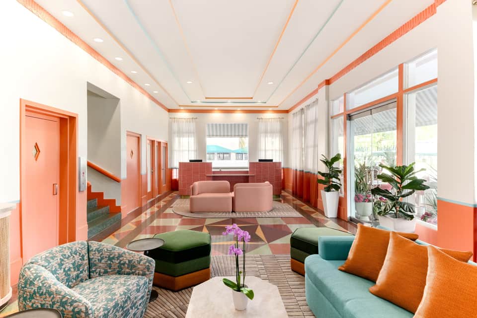Colorful hotel lobby with coral accents, geometric patterns, and contemporary furniture