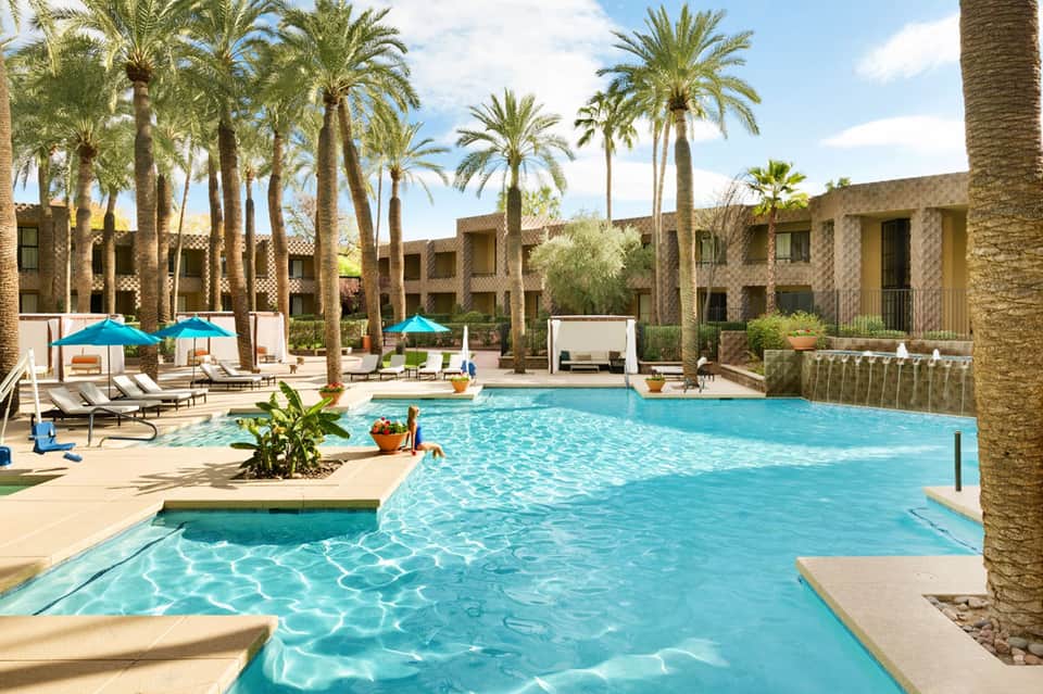 Resort courtyard with turquoise swimming pool, palm trees, and desert architecture