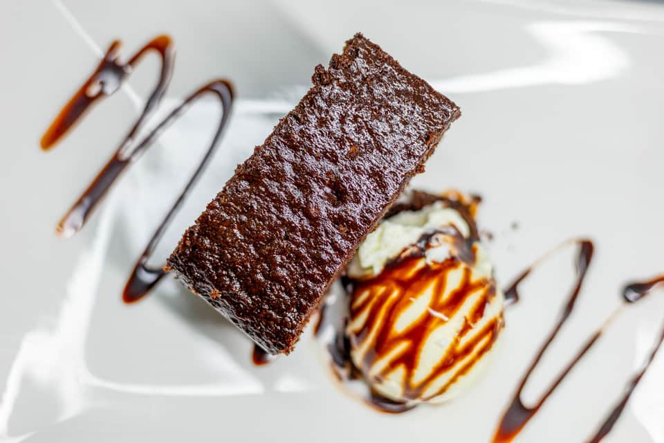 Elegant chocolate cake slice and dessert with chocolate drizzle on white plate