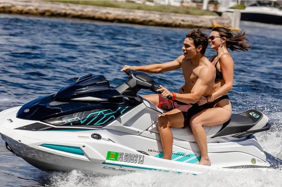 Couple on jet ski in blue water near dock and houses on sunny day