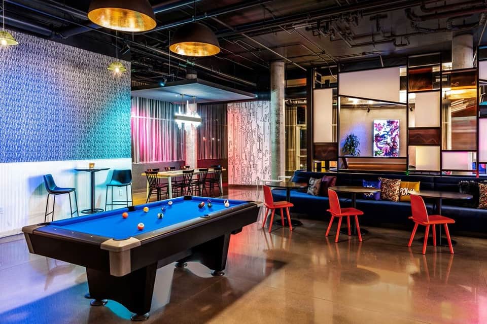 Game room with blue pool table, neon lighting, pink accent walls, and modern furniture
