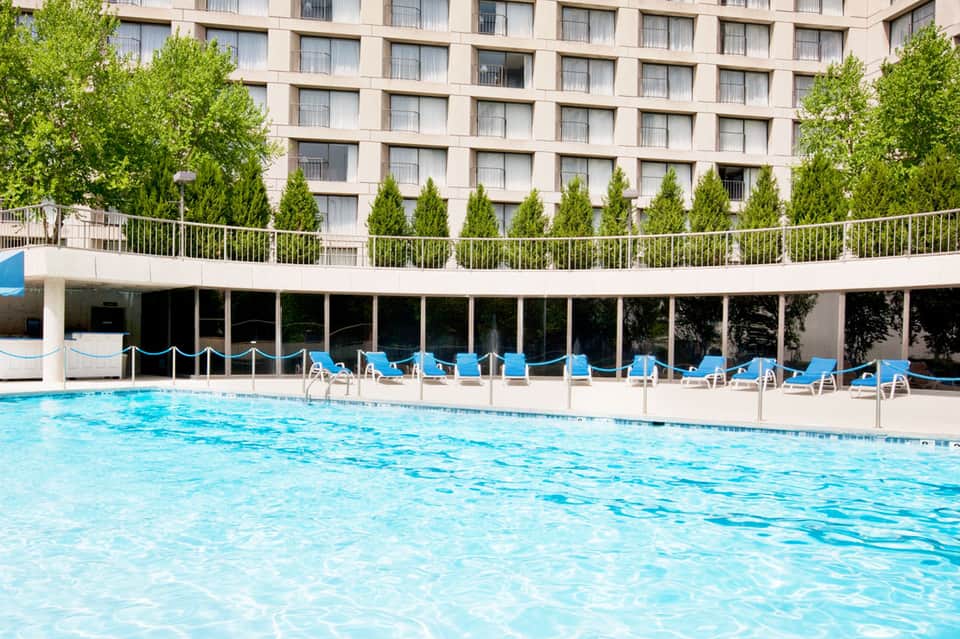 Resort pool with clear blue water, lounge chairs, and multi-story hotel building with manicured landscaping