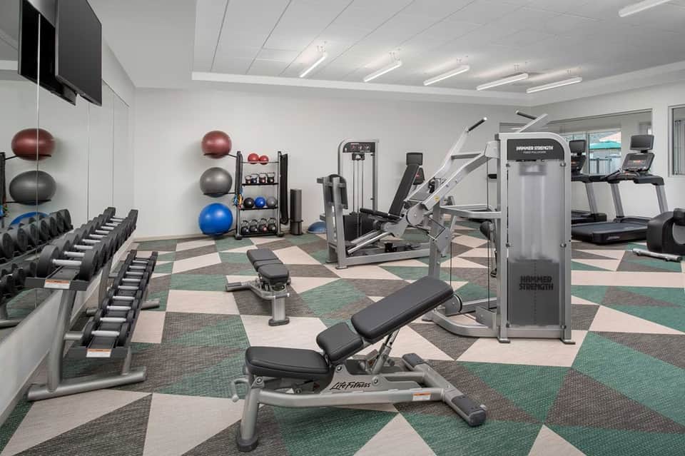 Fitness center with treadmills, weights, exercise balls, and colorful geometric carpet pattern
