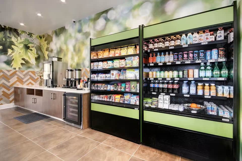 Hotel market convenience store with refrigerated vending machines, coffee station, and snack displays