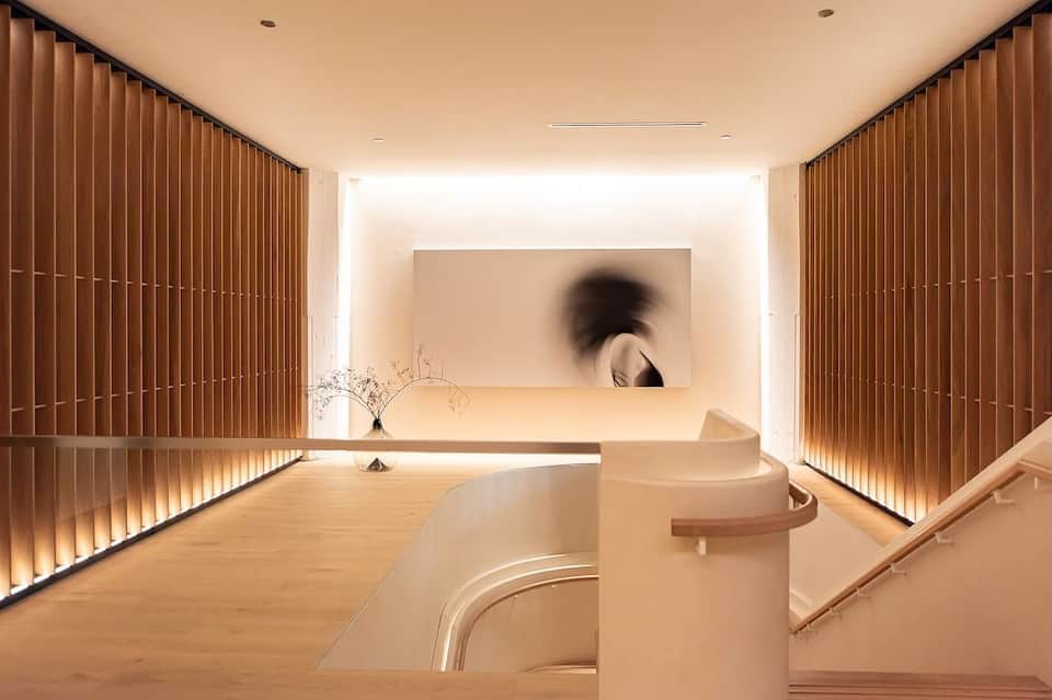 Modern staircase with wooden railings and warm lighting in minimalist hotel corridor