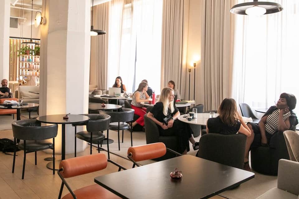 Contemporary hotel common area with comfortable seating and floor-to-ceiling curtains