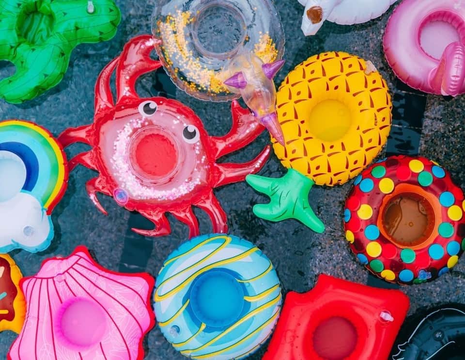 Colorful inflatable pool floats including crab, donut, and shell designs in water