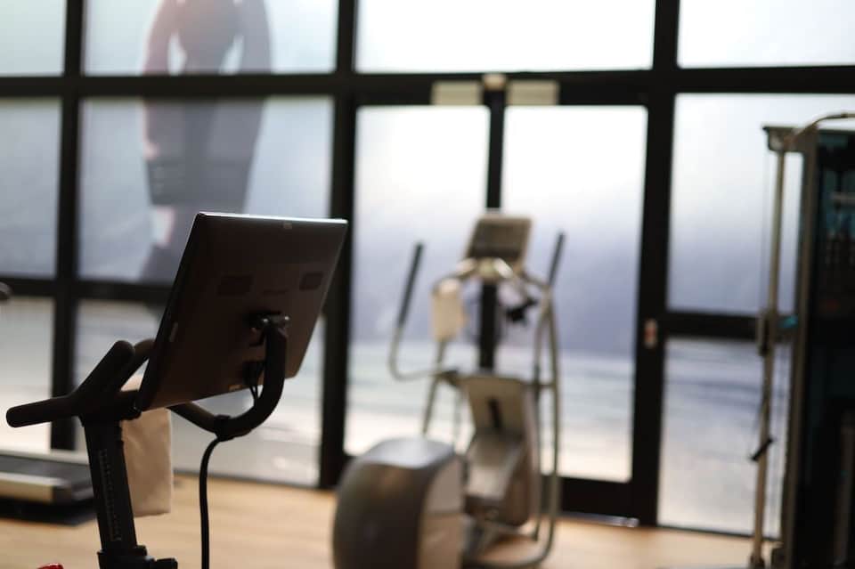Exercise bikes in fitness studio with floor-to-ceiling windows overlooking a scenic landscape