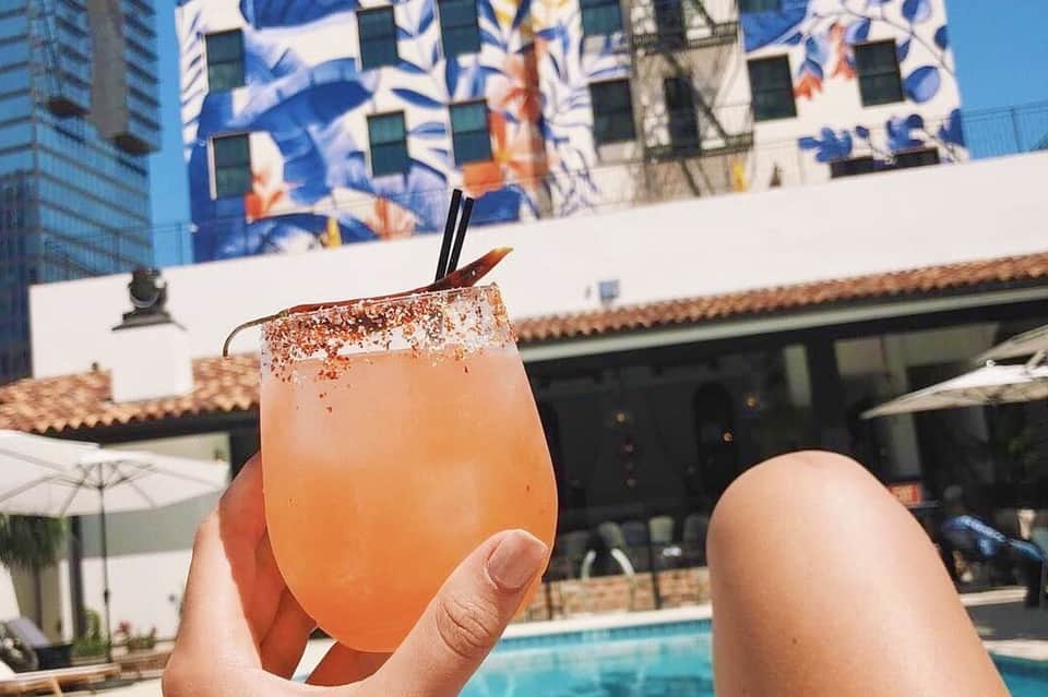 Colorful cocktail with cinnamon rim held poolside with resort buildings in background