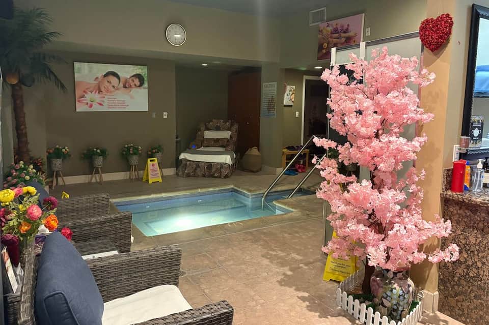 Indoor spa pool area decorated with pink flowers, seating area, and soft ambient lighting