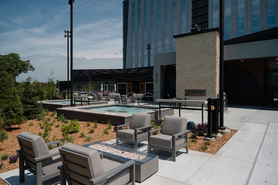 Rooftop pool and fire pit lounge with modern hotel building, landscaping, and evening ambiance