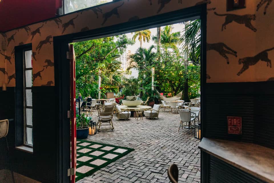 Courtyard patio with tropical plants and seating area viewed through open glass doors