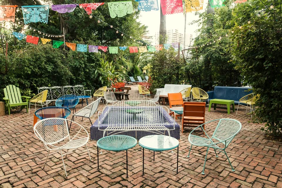 Bohemian courtyard with colorful papel picado, multicolored chairs, and lush greenery