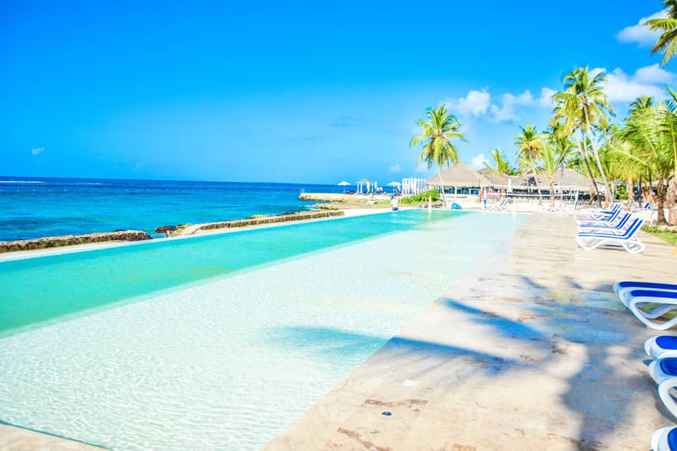 Crystal clear lagoon pool with white sand beach, palm trees, and lounge chairs