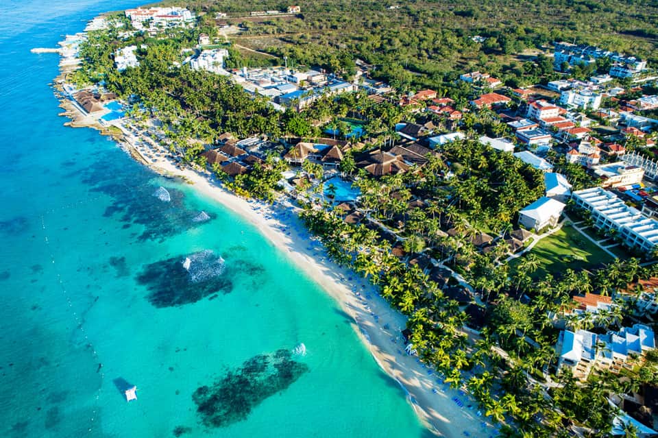 Aerial view of beachfront resort with turquoise waters, white sand beach, and lush tropical vegetation