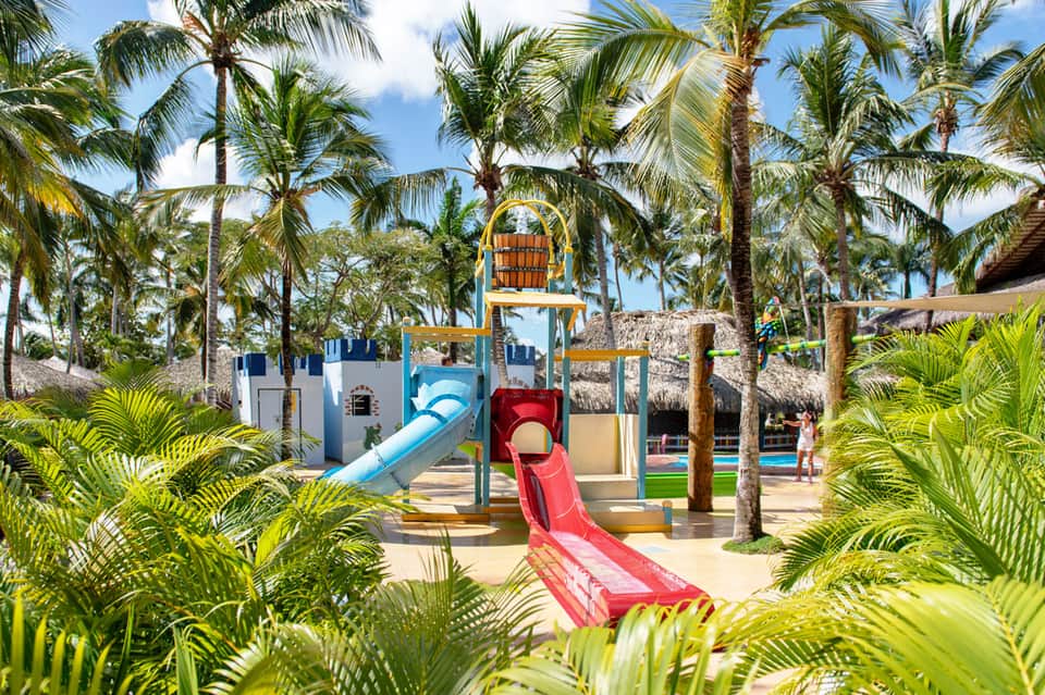 Colorful playground with slides and castle structure surrounded by palm trees