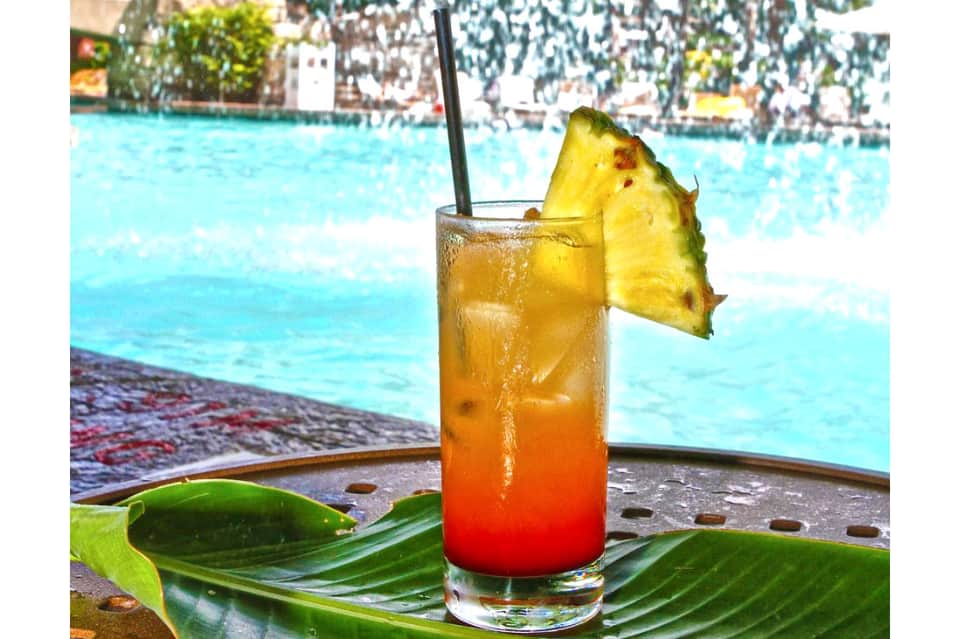 Tropical cocktail with pineapple garnish by resort pool