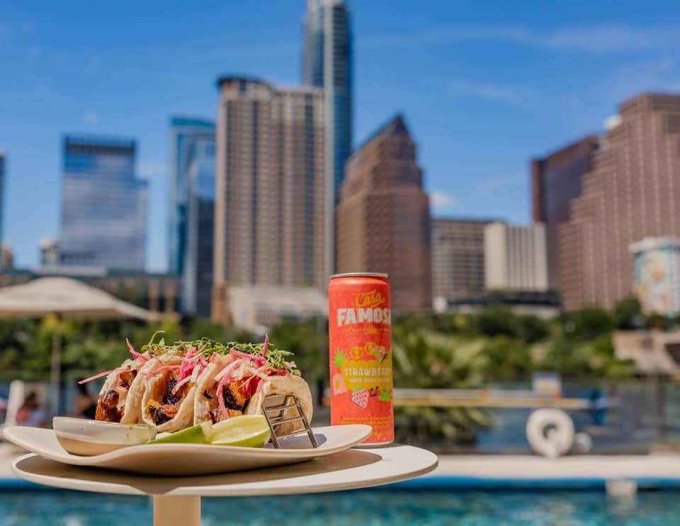 Gourmet tacos and strawberry beverage served poolside with urban skyline and water views