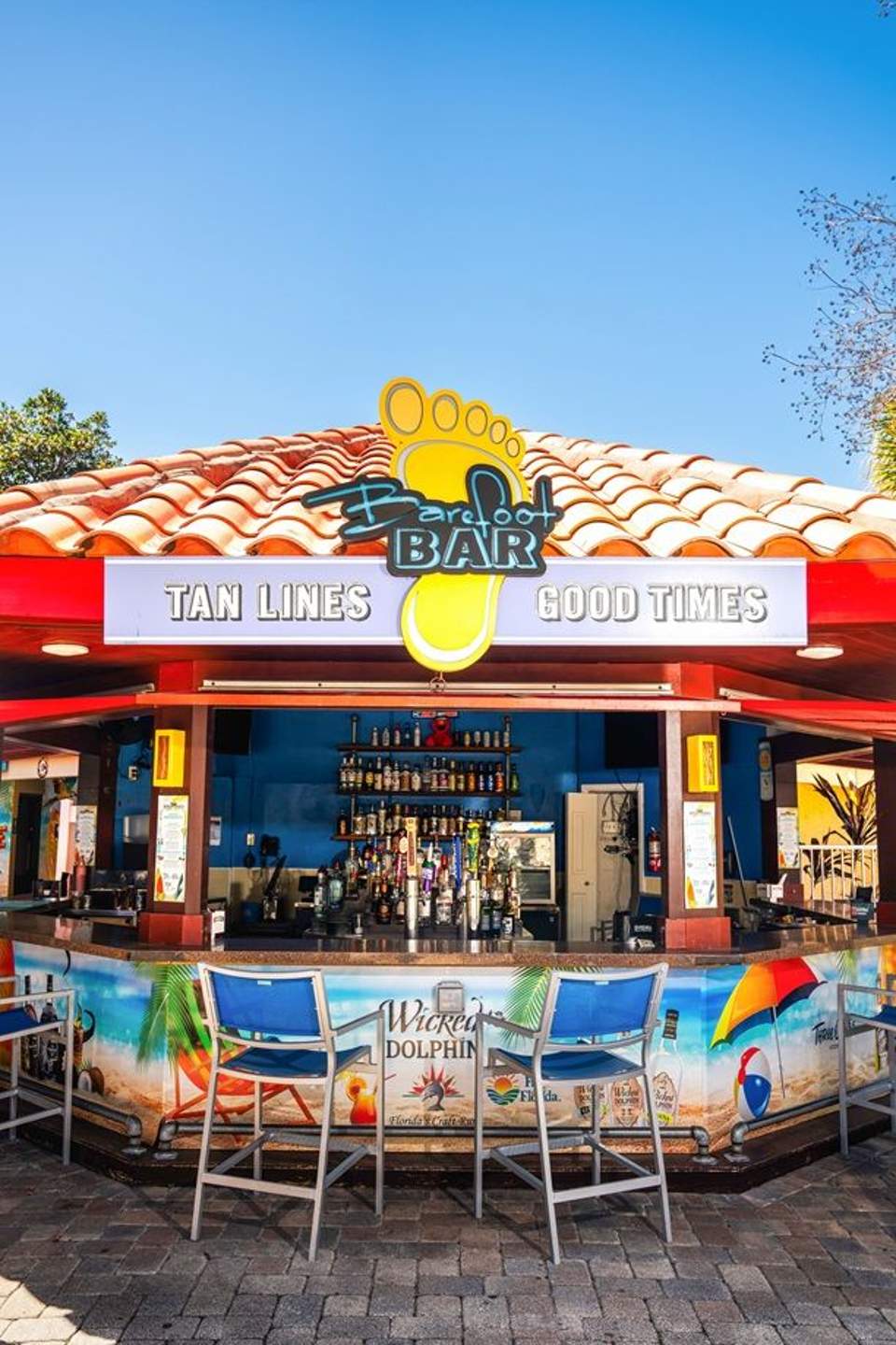 Colorful beach bar with blue and red exterior, tan lines signage, tropical setting