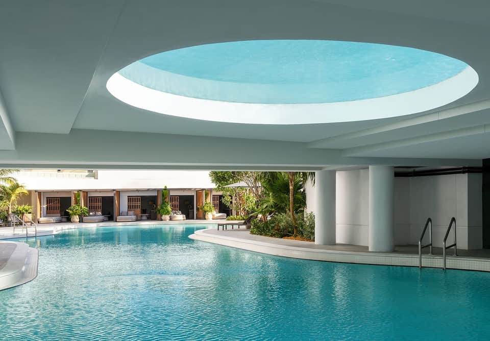 Indoor swimming pool with circular skylight ceiling and covered lounging area