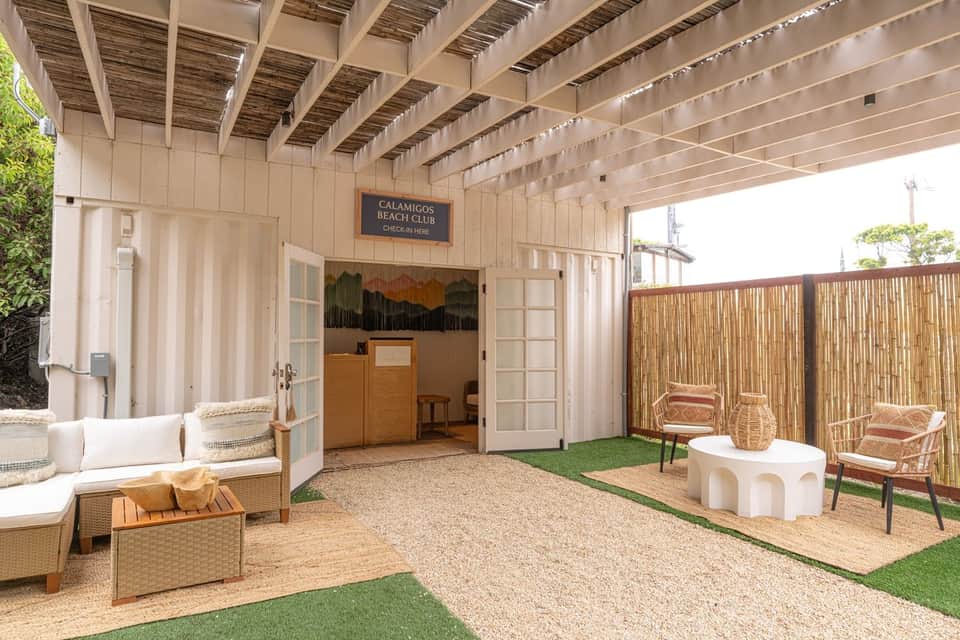 Covered beach club pavilion with cream-colored furniture, woven accents, and bamboo privacy screens
