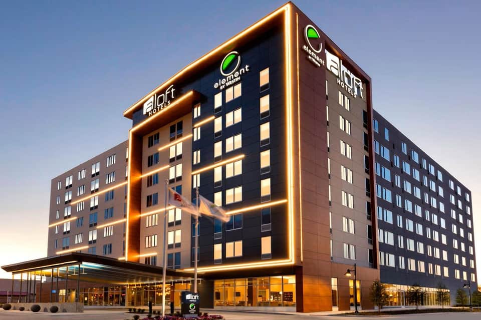 Modern hotel exterior at night with illuminated gold signage and multi-story facade