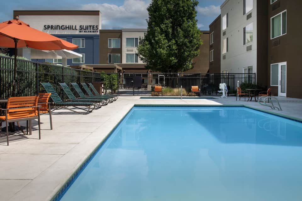 Springhill Suites outdoor pool area with lounge chairs, orange umbrella, and multi-story hotel building