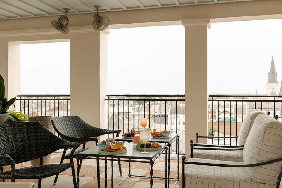 Covered rooftop lounge with contemporary furniture, panoramic city views, and ceiling fans