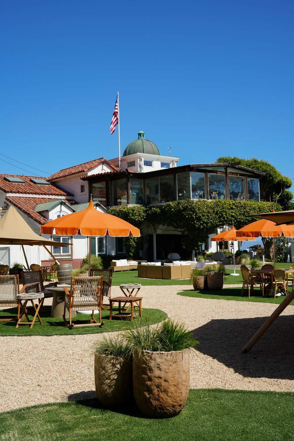 Coastal resort with orange umbrellas, lawn seating area, and building with green dome