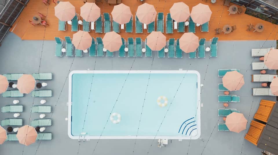 Overhead view of rectangular pool surrounded by teal loungers and peach umbrellas on deck