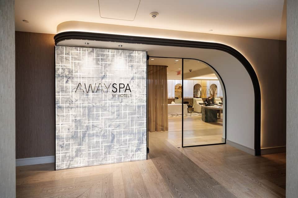 Away Spa entrance with illuminated signage and curved glass doors in hotel corridor