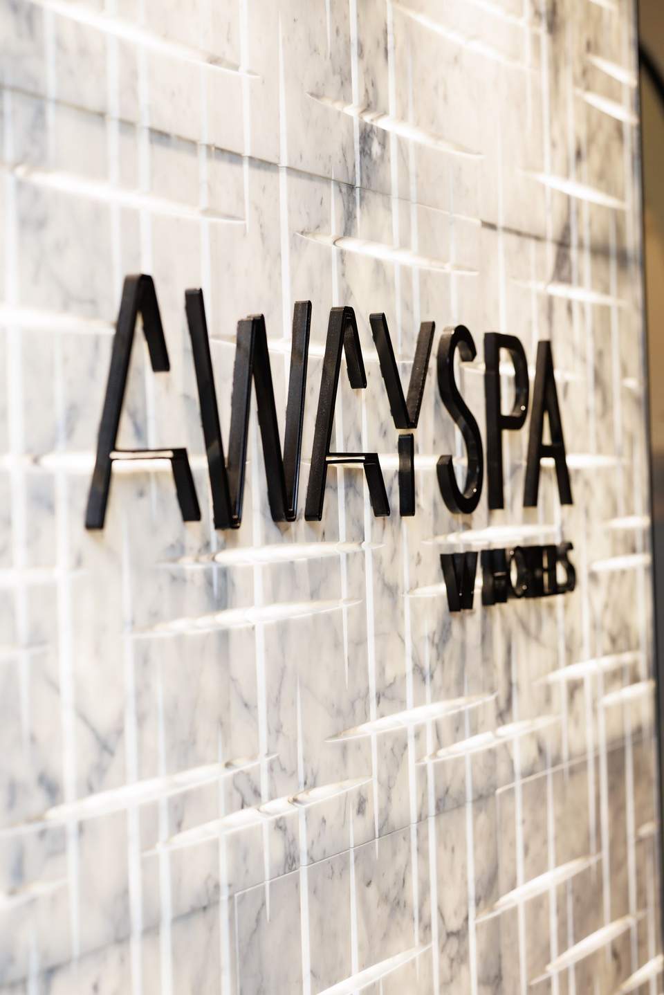 Away Spa signage mounted on marble subway tile wall with natural light