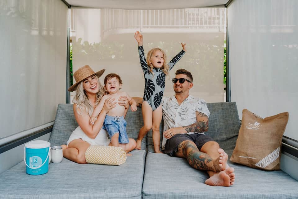 Family of four relaxing on gray couch in modern screened outdoor living space
